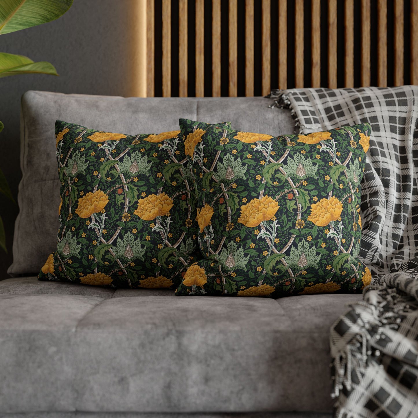 Decorative pillows with floral pattern on a gray sofa against a wooden headboard.