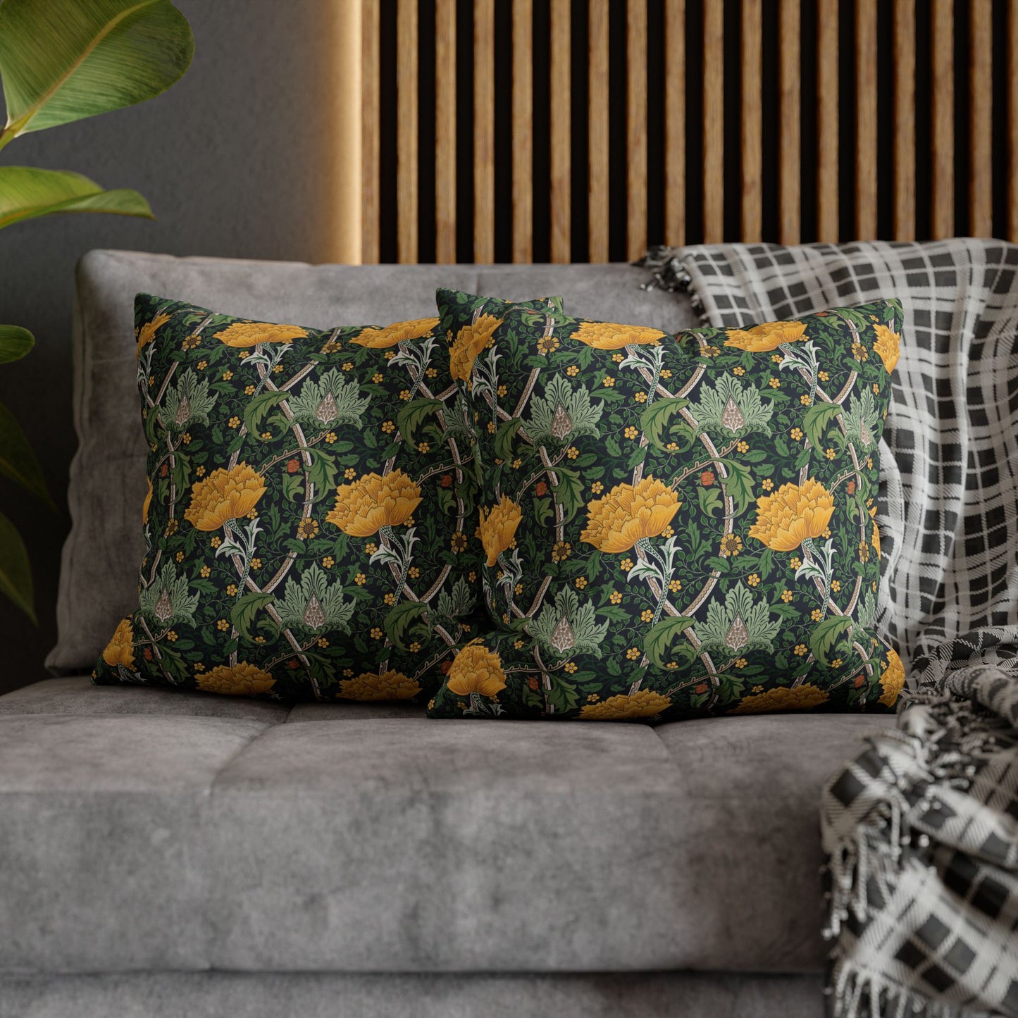 Decorative pillows with floral pattern on a gray sofa against a wooden panel wall.