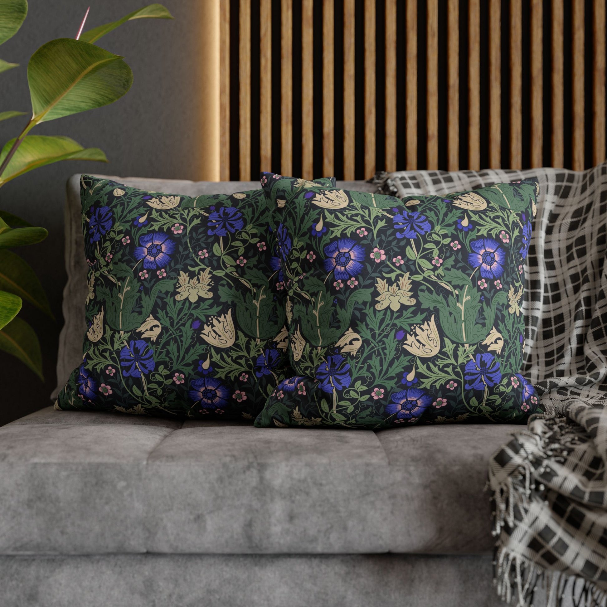 Floral patterned cushions on a sofa with a plant and wooden panel in the background
