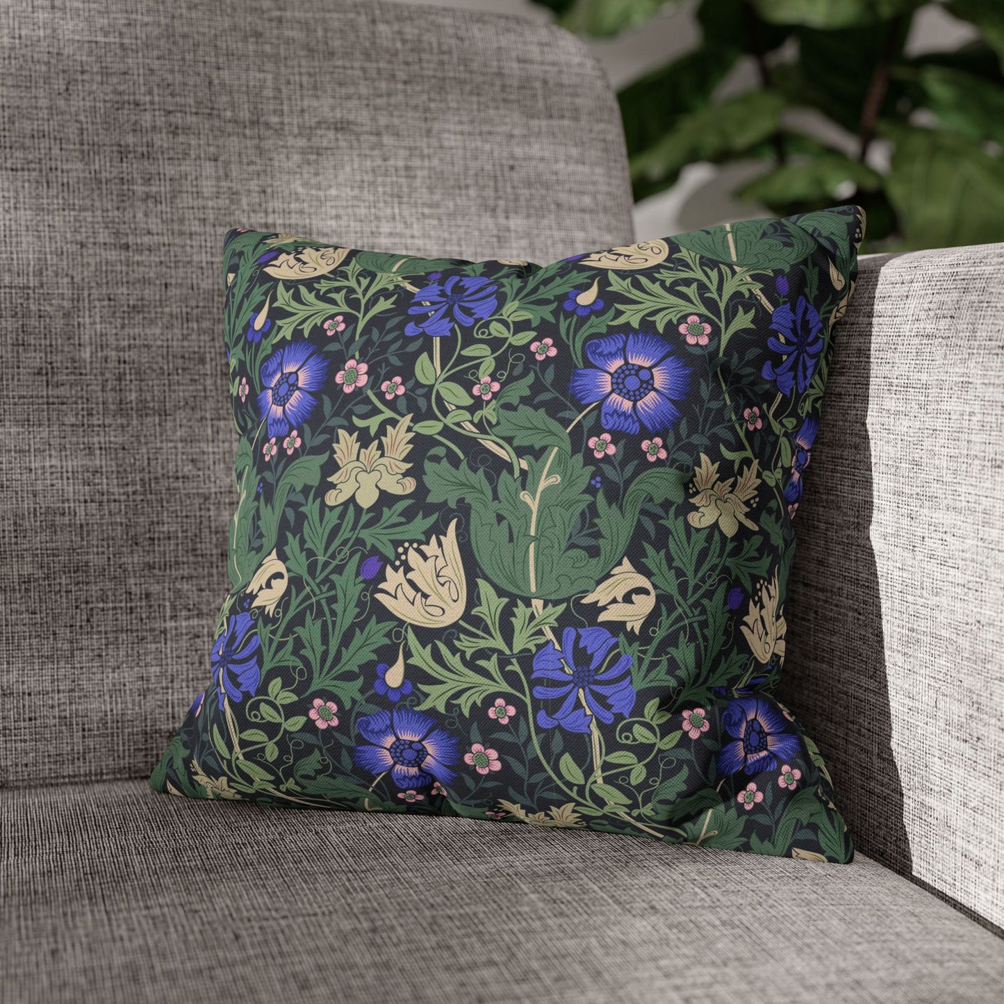 Floral patterned pillow on a gray sofa with greenery in the background