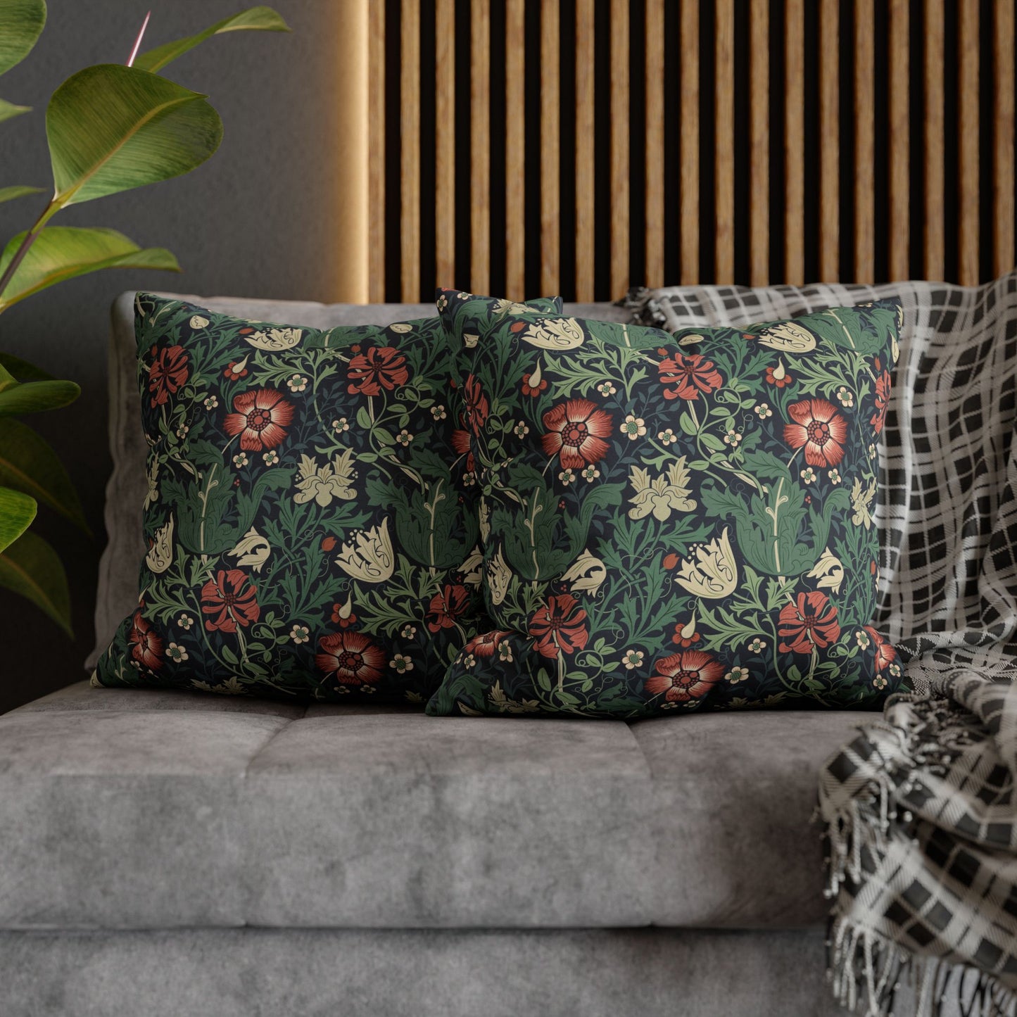 Floral patterned cushions on a gray sofa with a wooden headboard and plant in the background