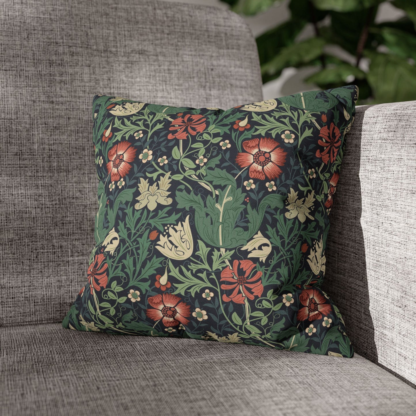 Floral patterned pillow on a gray sofa with a blurred green plant background