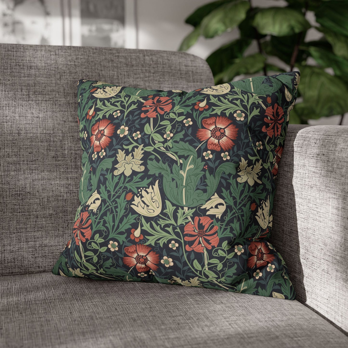 Floral patterned pillow on a gray sofa with a blurred plant in the background