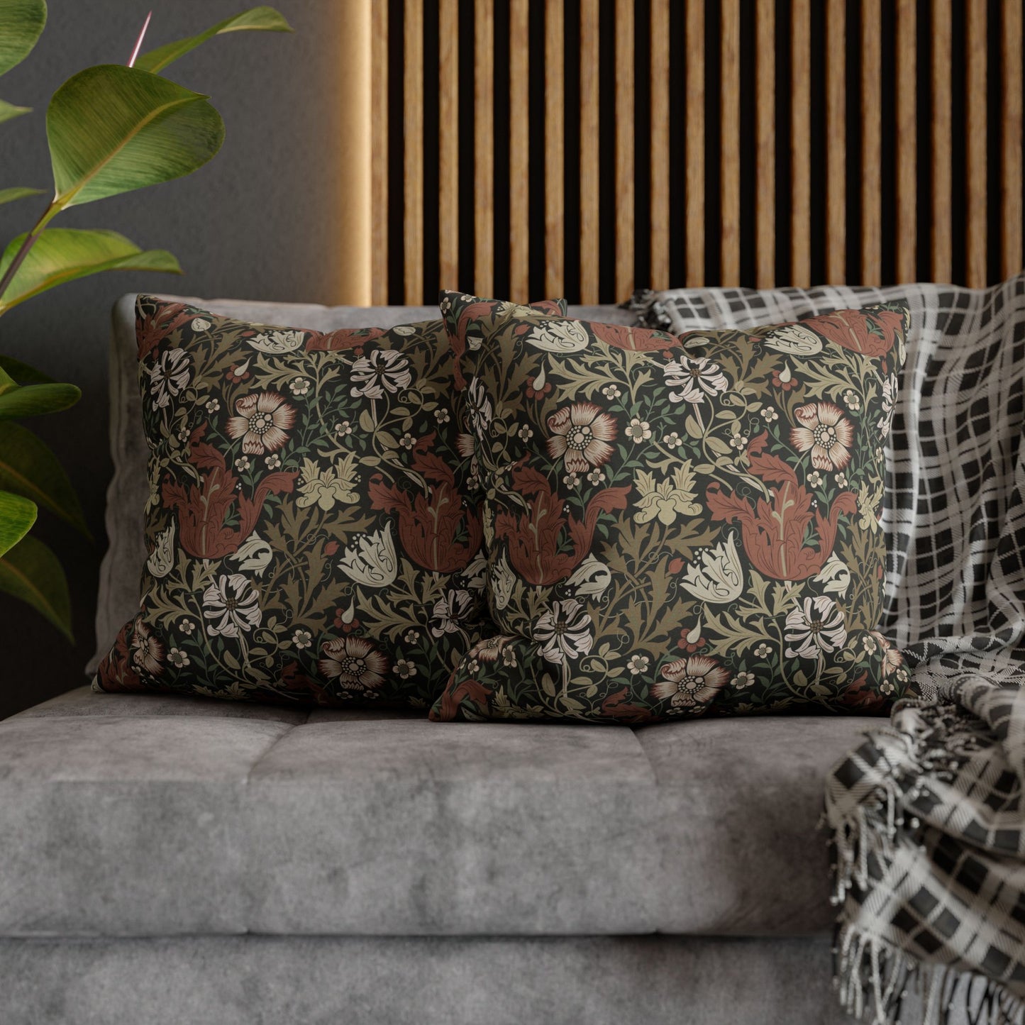 Decorative pillows with floral patterns on a gray sofa against a wooden slat wall.