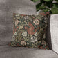 Floral patterned pillow on a gray sofa with a blurred green plant in the background