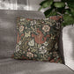 Floral patterned pillow on a gray sofa with a blurred plant in the background