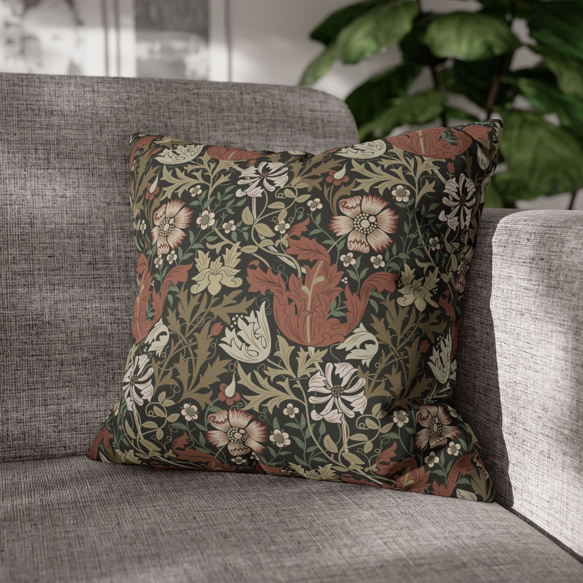 Floral patterned pillow on a gray sofa with a blurred plant in the background
