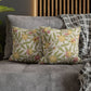 Floral patterned cushions on a gray sofa with a wooden headboard in the background.