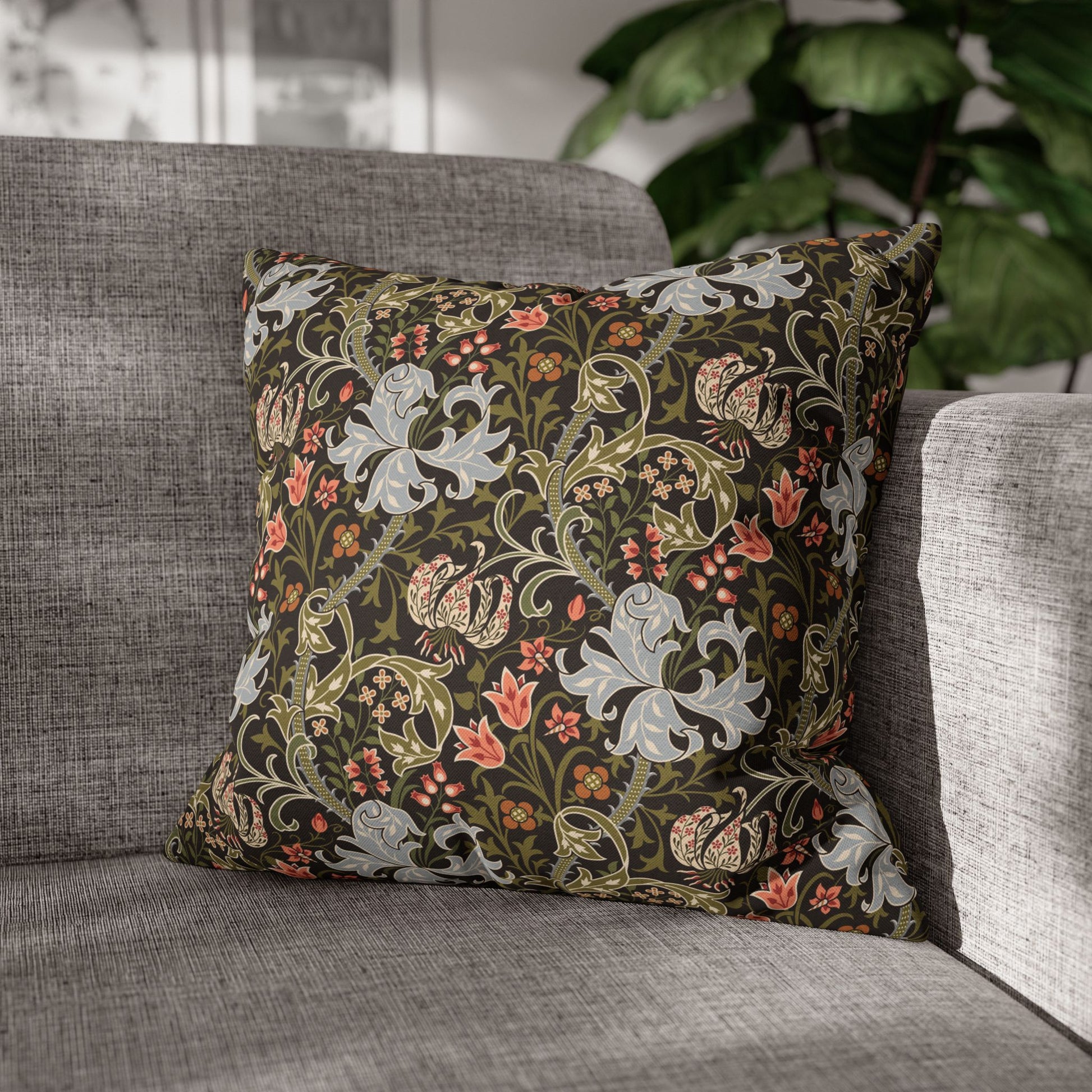 Decorative floral pillow on a gray sofa with a blurred indoor background