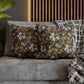 Decorative pillows with floral patterns on a gray sofa against a wooden headboard.