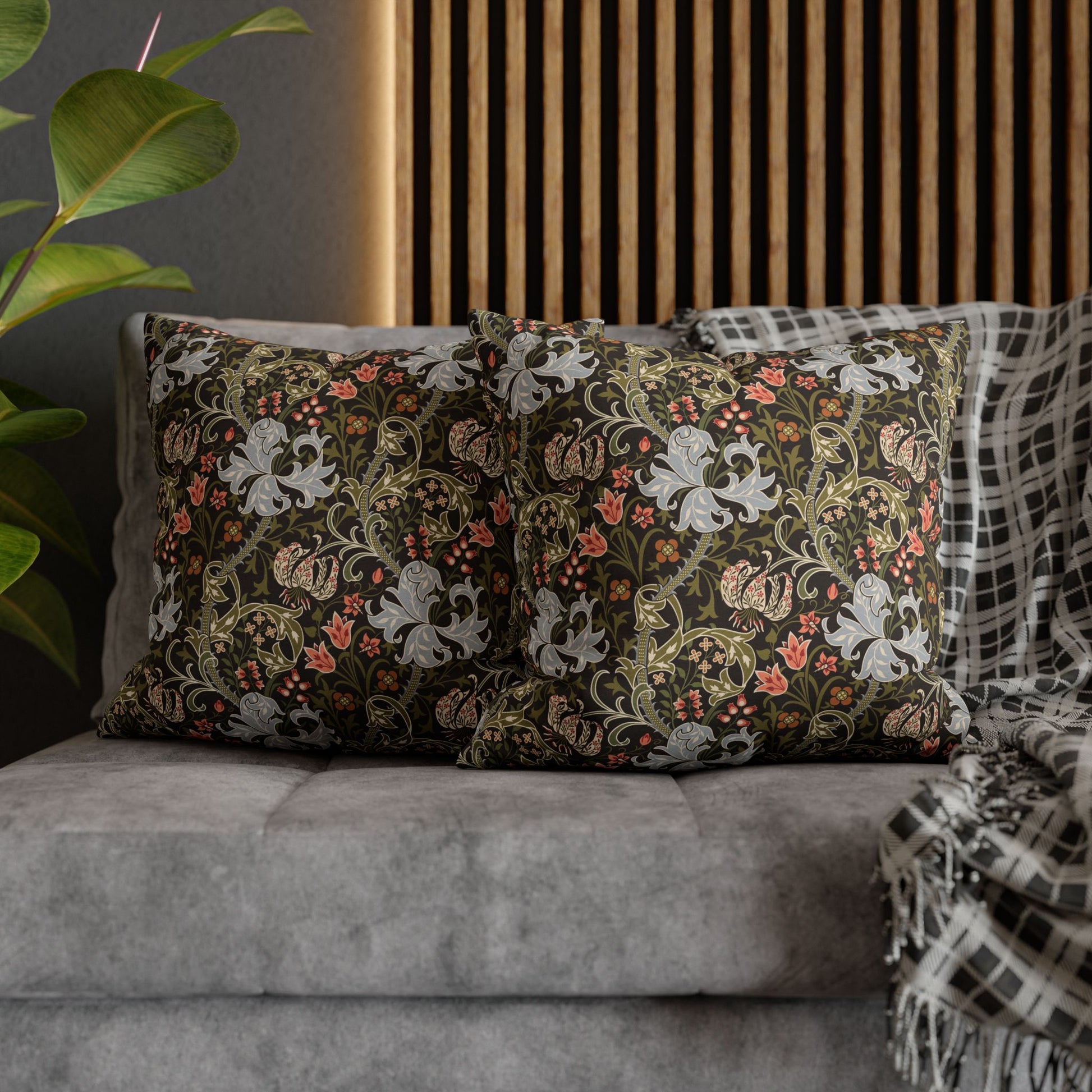 Decorative pillows with floral patterns on a gray sofa against a wooden panel wall.