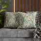 Decorative pillows with floral patterns on a gray sofa next to a plant.