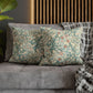 Decorative pillows with floral patterns on a gray sofa against a wooden headboard.