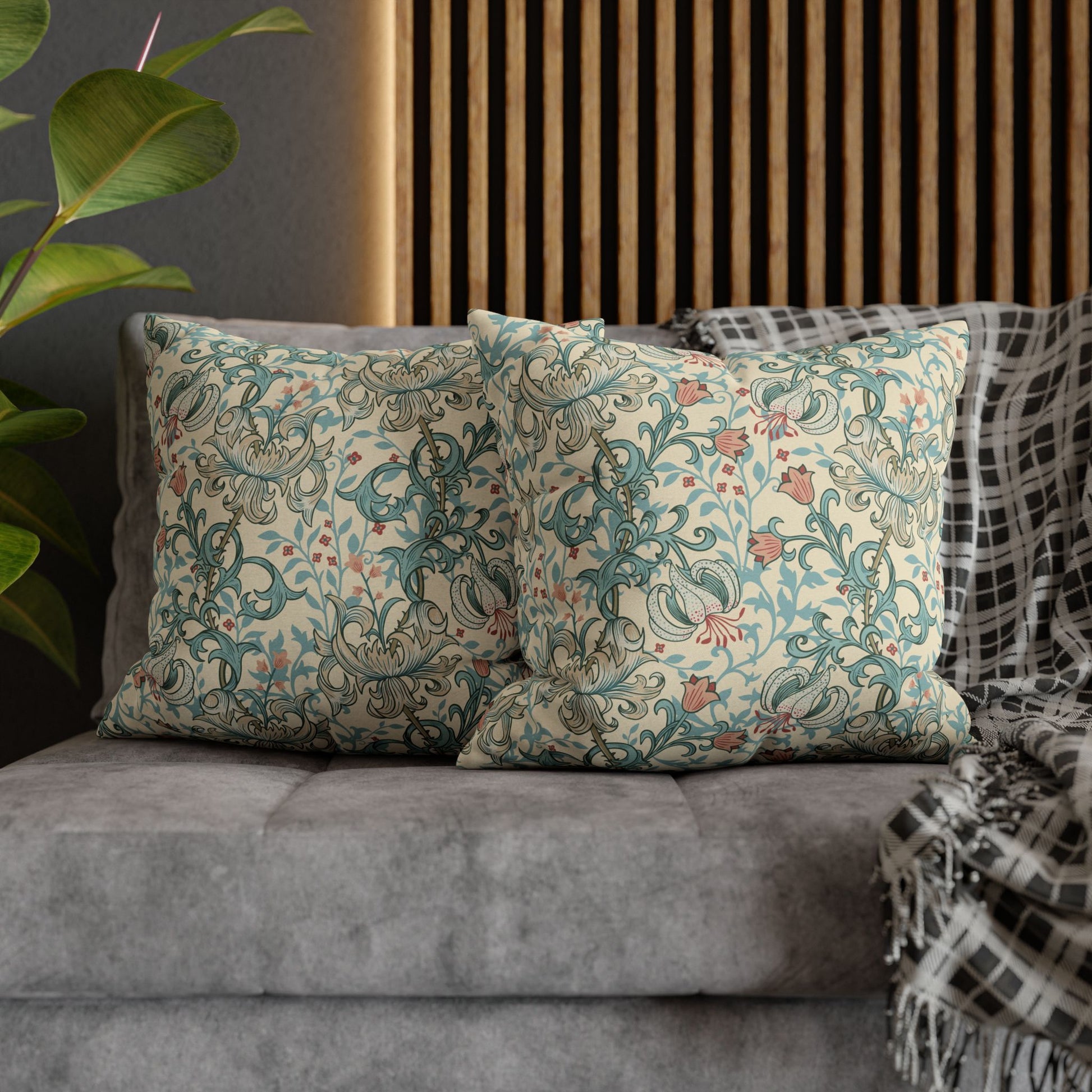 Decorative pillows with floral patterns on a gray sofa next to a plant.