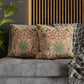 Floral patterned cushions on a gray sofa with a wooden headboard and plant in the background