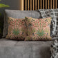 Floral patterned cushions on a gray sofa with a wooden headboard in the background.