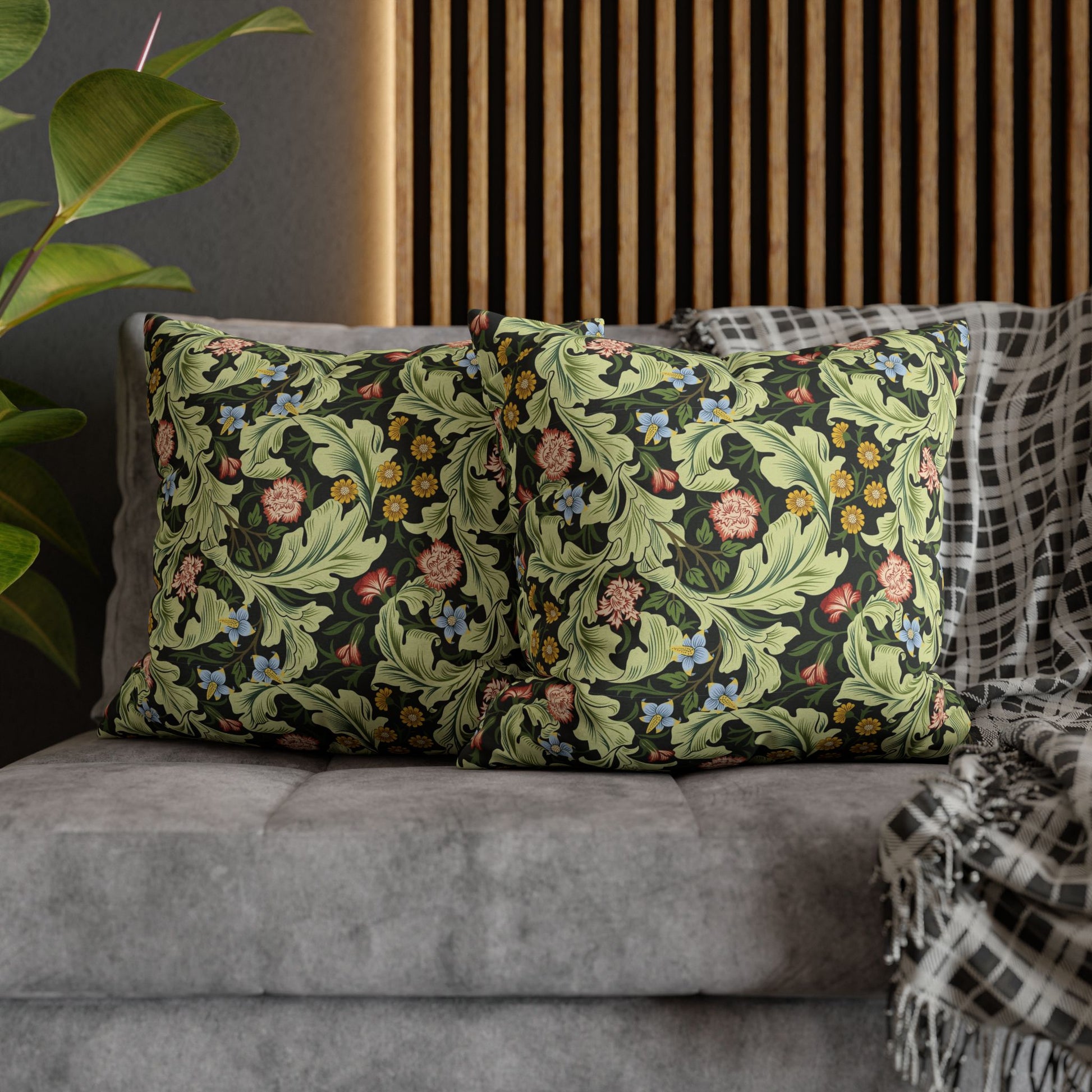 Decorative pillows with floral patterns on a gray sofa against a wooden panel wall - William Morris Leicester