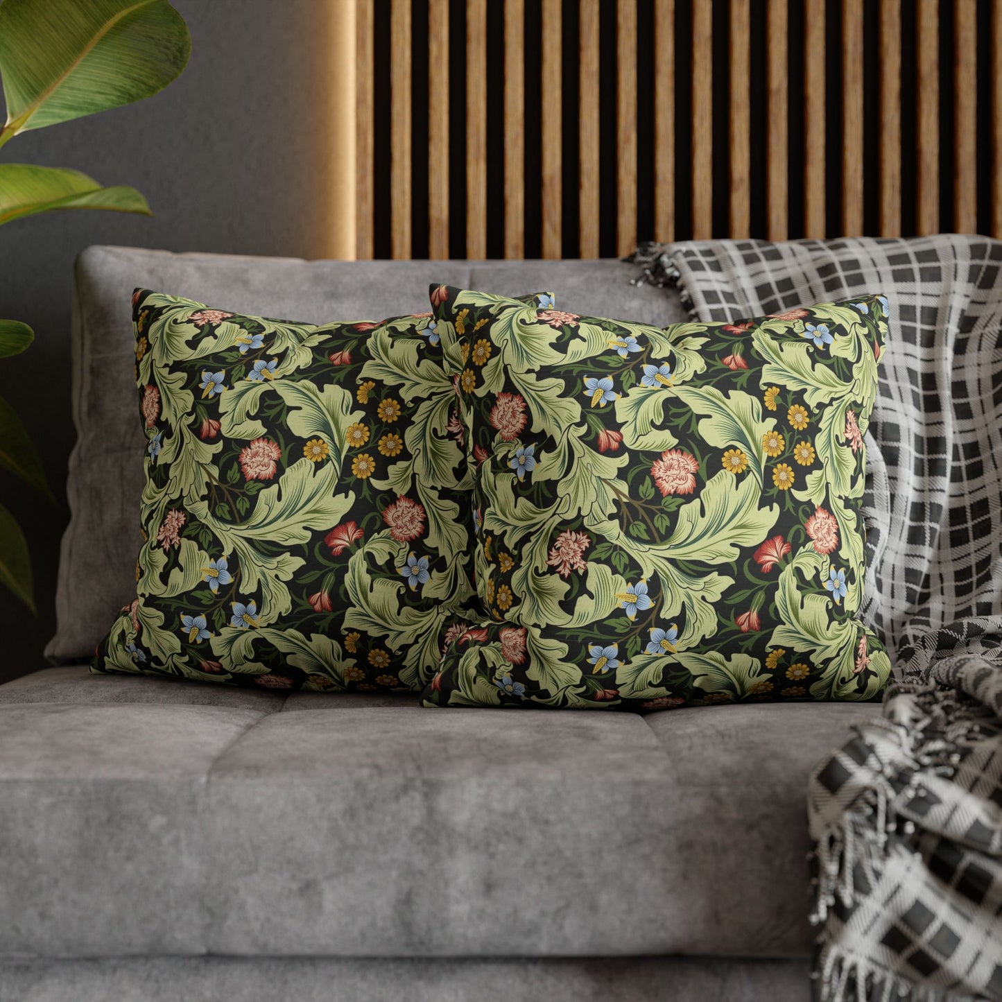 Floral patterned pillows on a gray sofa with a wooden headboard in the background - William Morris Leicester