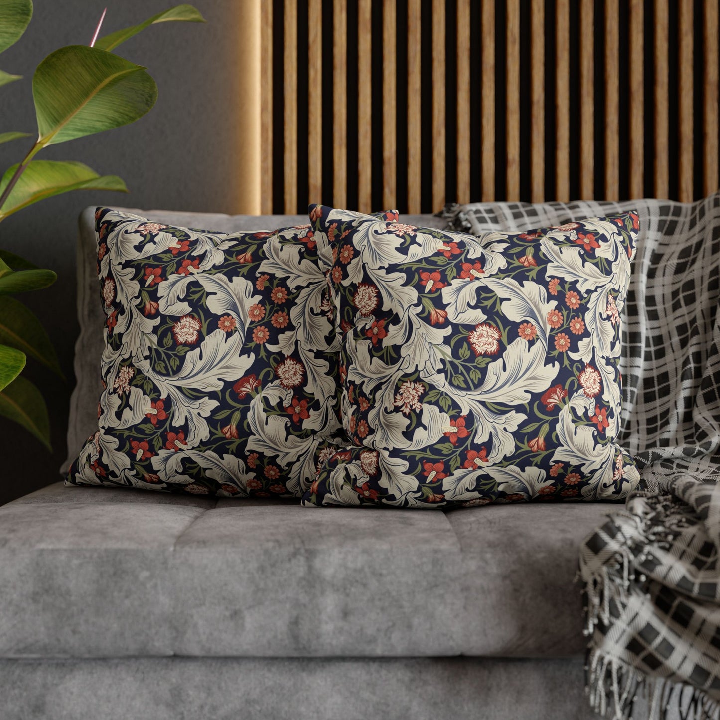 Decorative pillows with floral patterns on a gray sofa against a wooden slat wall.