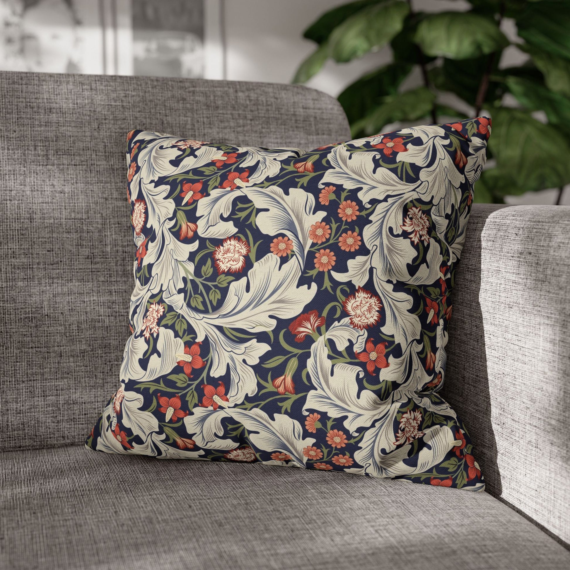 Decorative floral pillow on a gray sofa with a blurred plant in the background