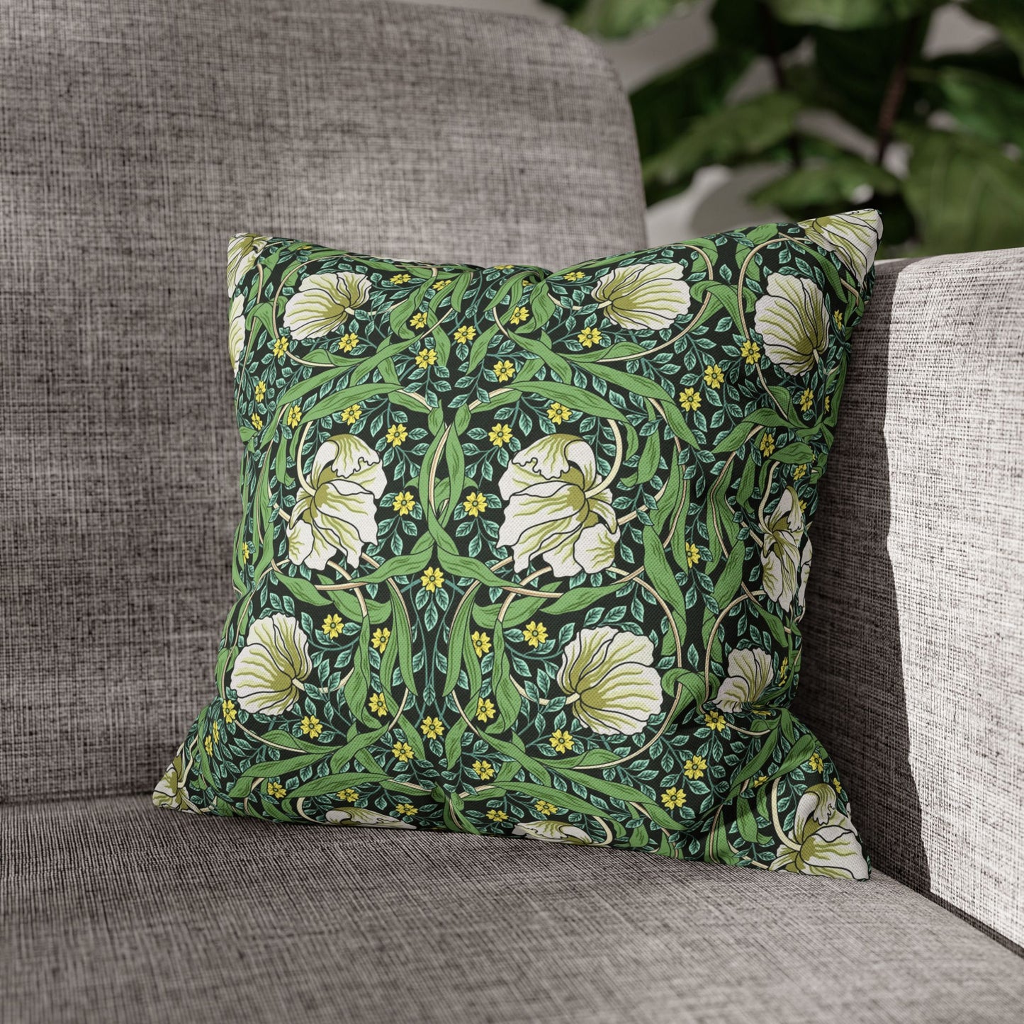 Floral patterned pillow on a gray sofa with greenery in the background