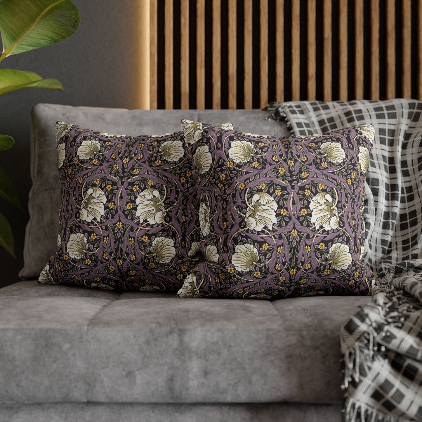 Decorative pillows with floral patterns on a gray sofa against a wooden panel wall.
