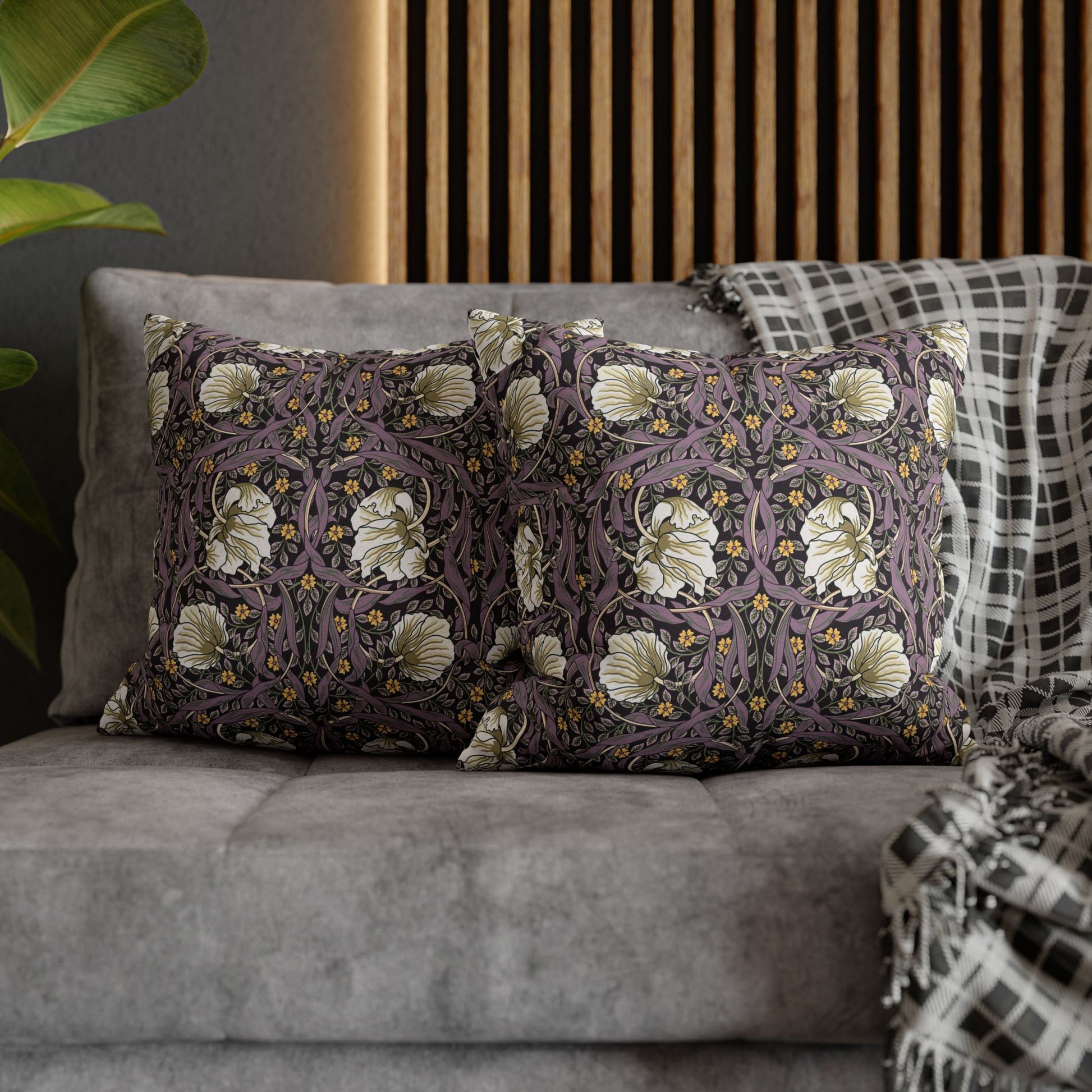 Decorative pillows with floral patterns on a gray sofa against a wooden panel wall.