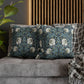 Decorative pillows with floral patterns on a gray sofa against a wooden slat wall.
