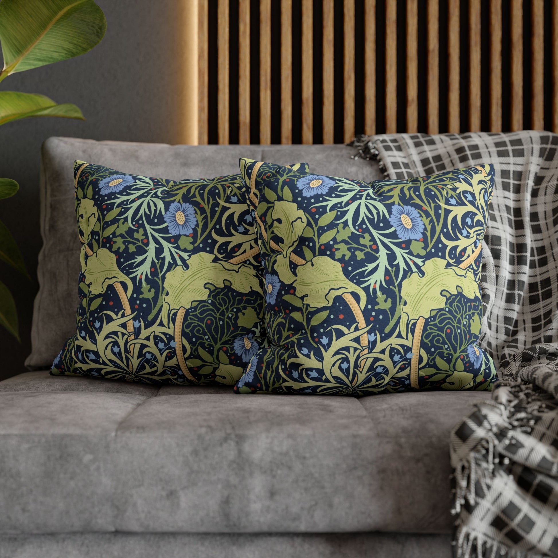 Decorative pillows with floral patterns on a gray sofa against a wooden panel wall.