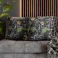 Decorative pillows with floral patterns on a gray sofa against a wooden slat wall.