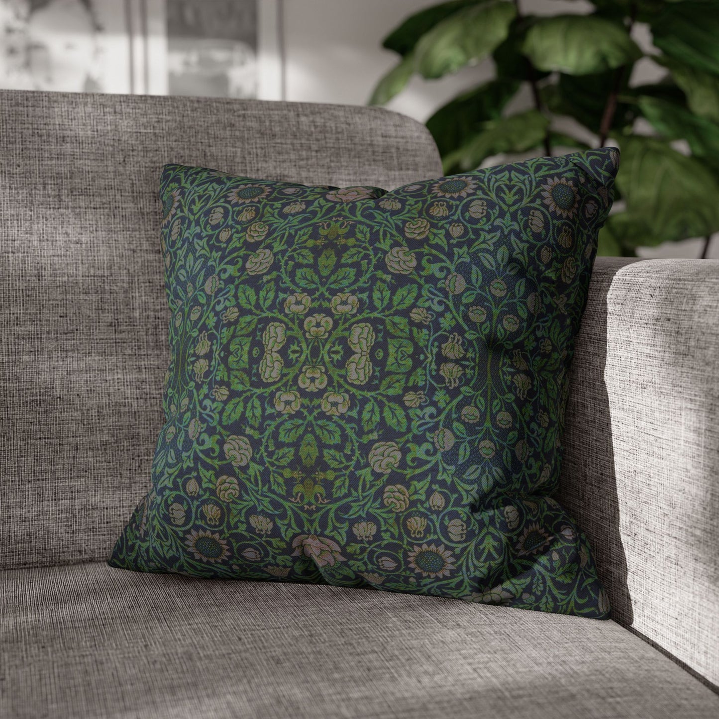 Green patterned pillow on a gray sofa with a blurred plant in the background