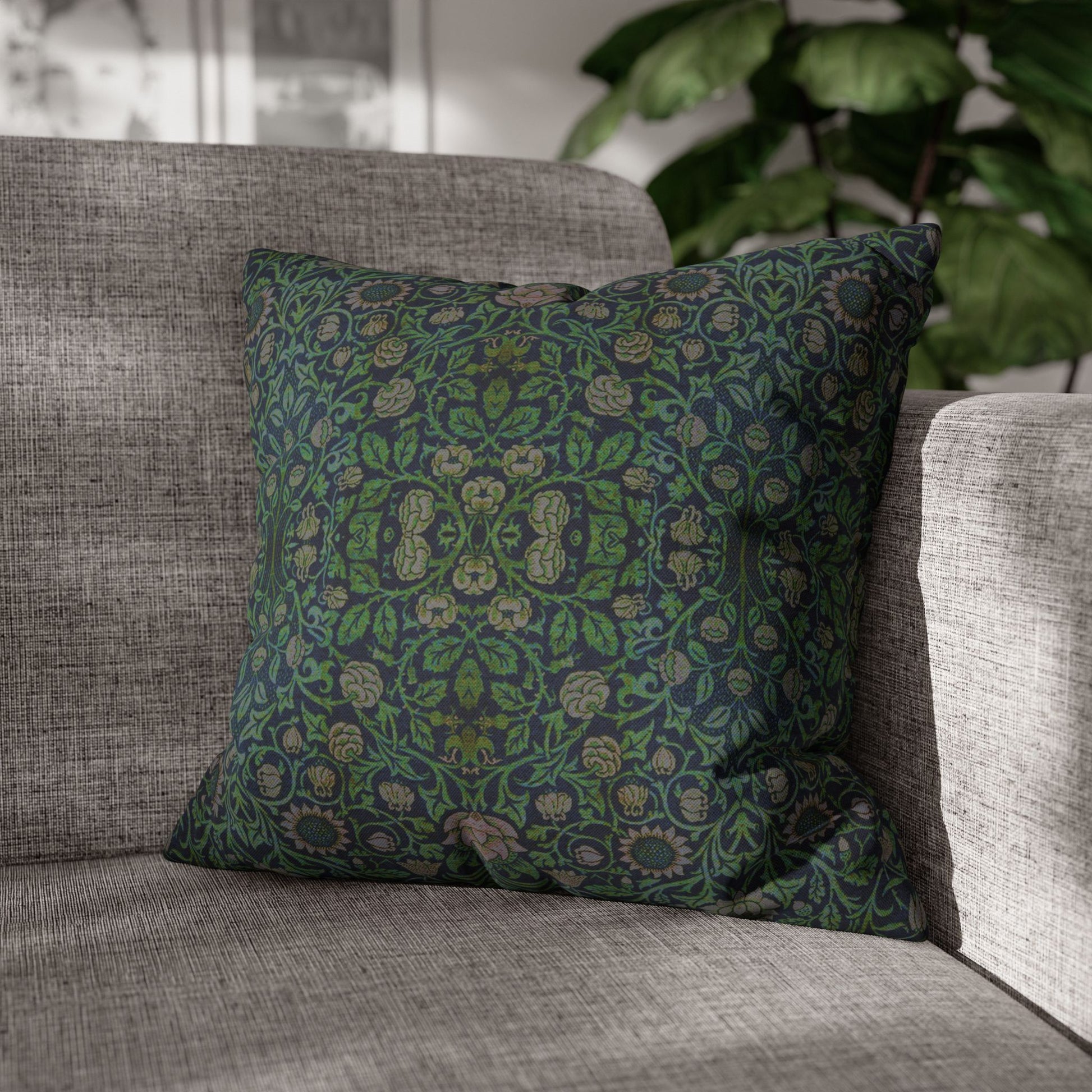 Green patterned pillow on a gray sofa with a blurred plant in the background