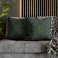 Decorative pillows with green patterns on a gray sofa against a wooden panel wall.