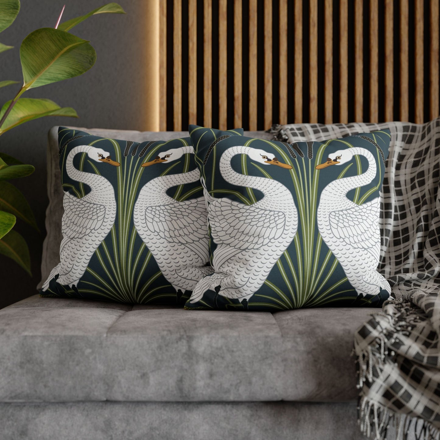 Decorative pillows with swan design on a gray sofa