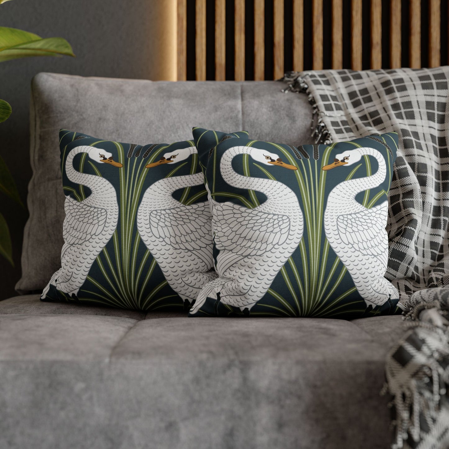 Decorative pillows with swan design on a gray sofa