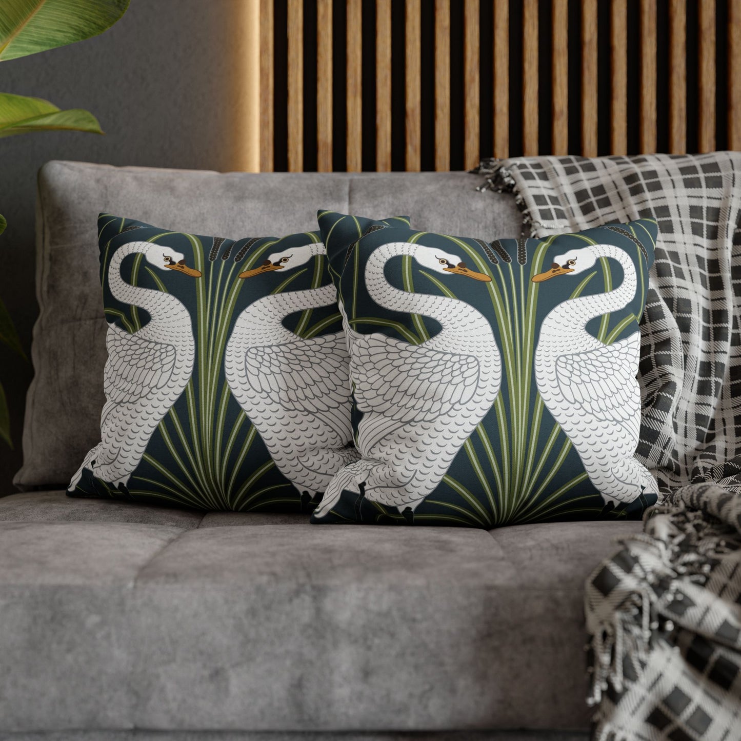 Decorative pillows with swan design on a gray sofa