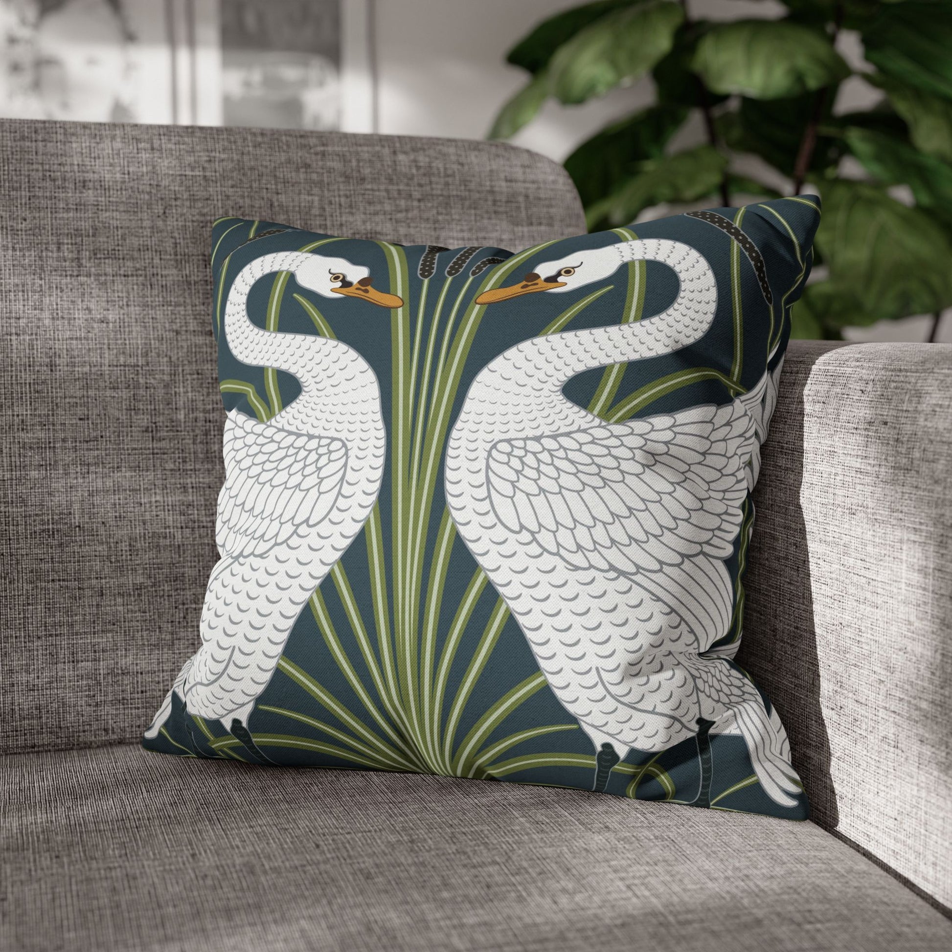 Decorative pillow with swan design on a gray sofa