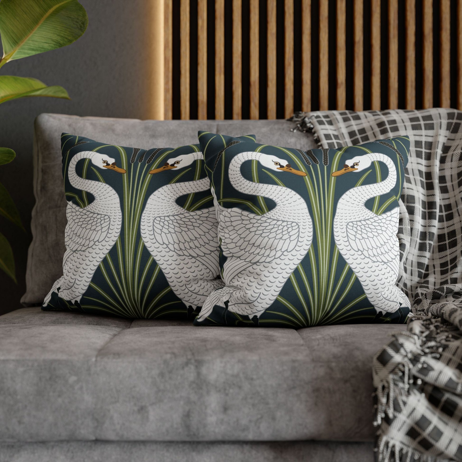 Decorative pillows with swan design on a gray sofa against a wooden panel background