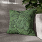 Green leaf-patterned pillow on a gray sofa with a blurred indoor background