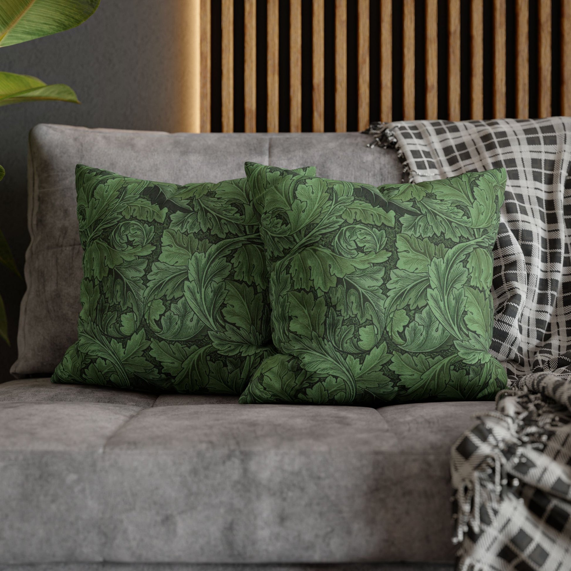 Green patterned pillows on a gray sofa with a wooden headboard in the background