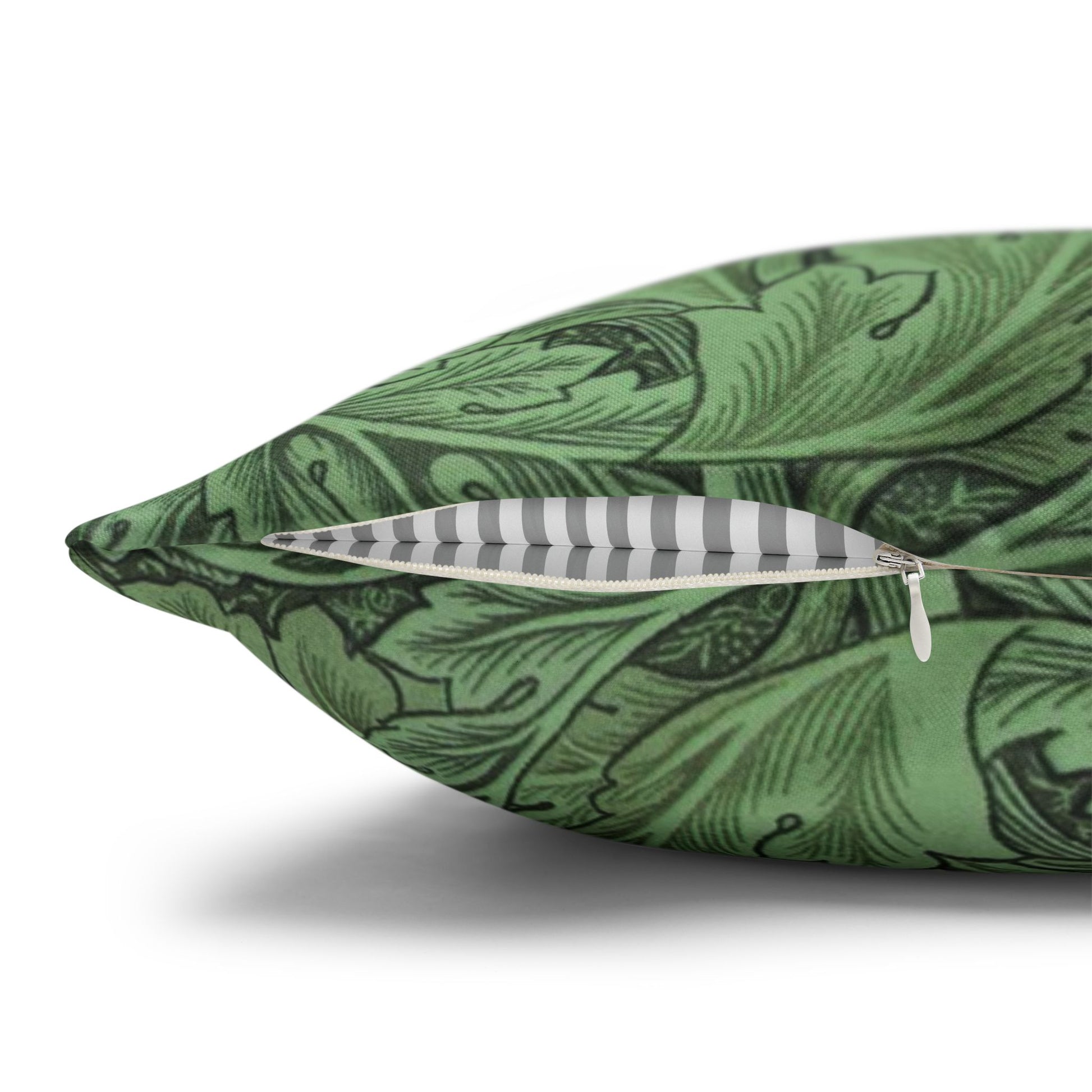 Green decorative pillow with black leaf pattern and a feather on a white background