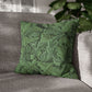 Green patterned pillow on a gray sofa with plants in the background