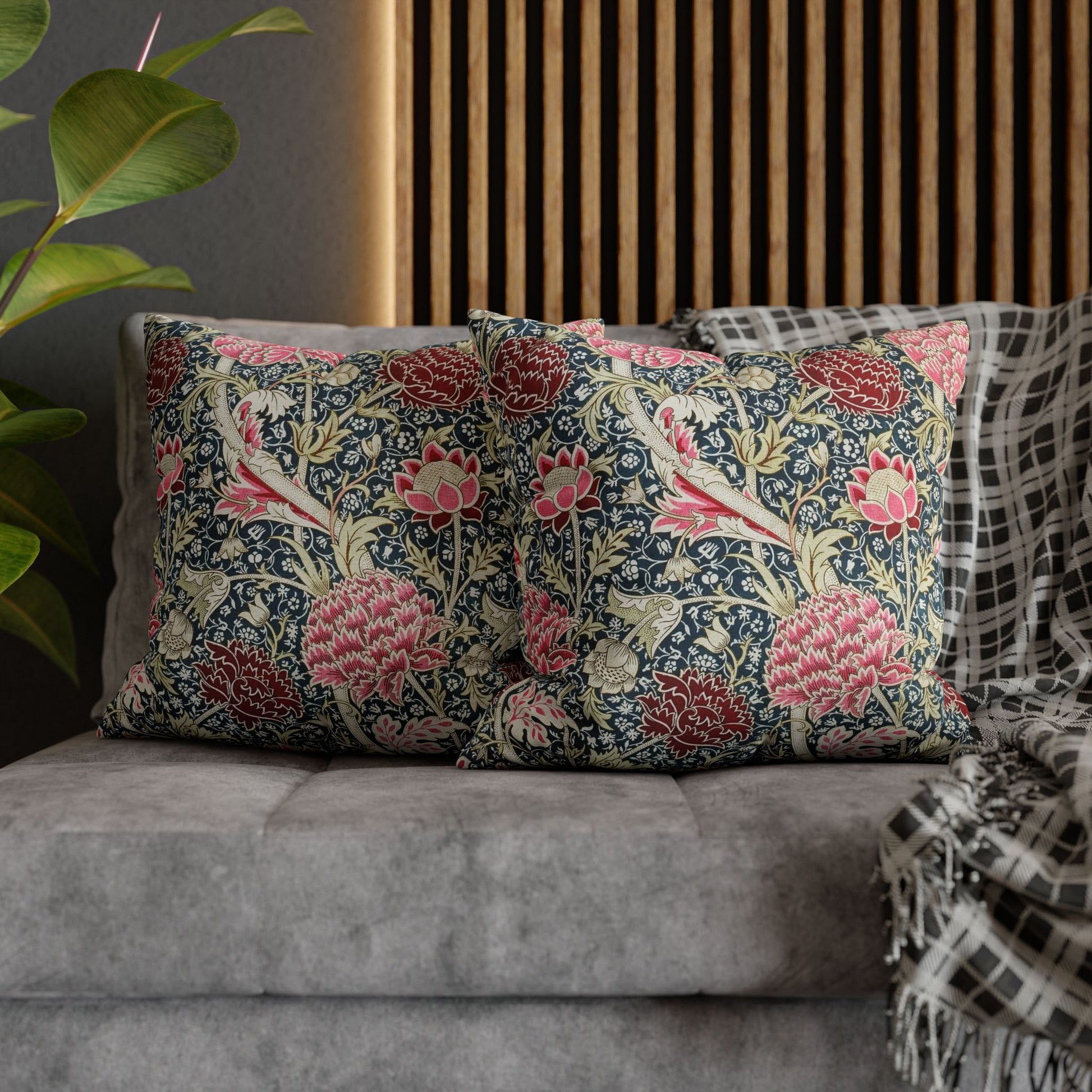 Floral patterned cushions on a sofa with a plant and wooden slat wall in the background