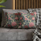 Floral patterned cushions on a gray sofa with a wooden headboard in the background.