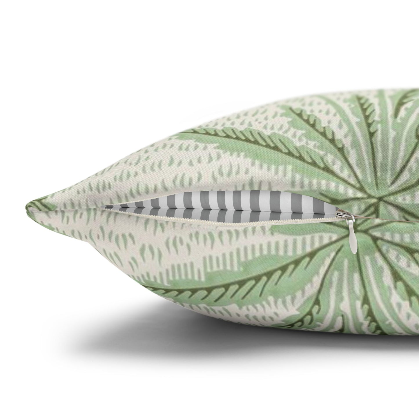 Green leaf-patterned pillow with a zipper on a white background