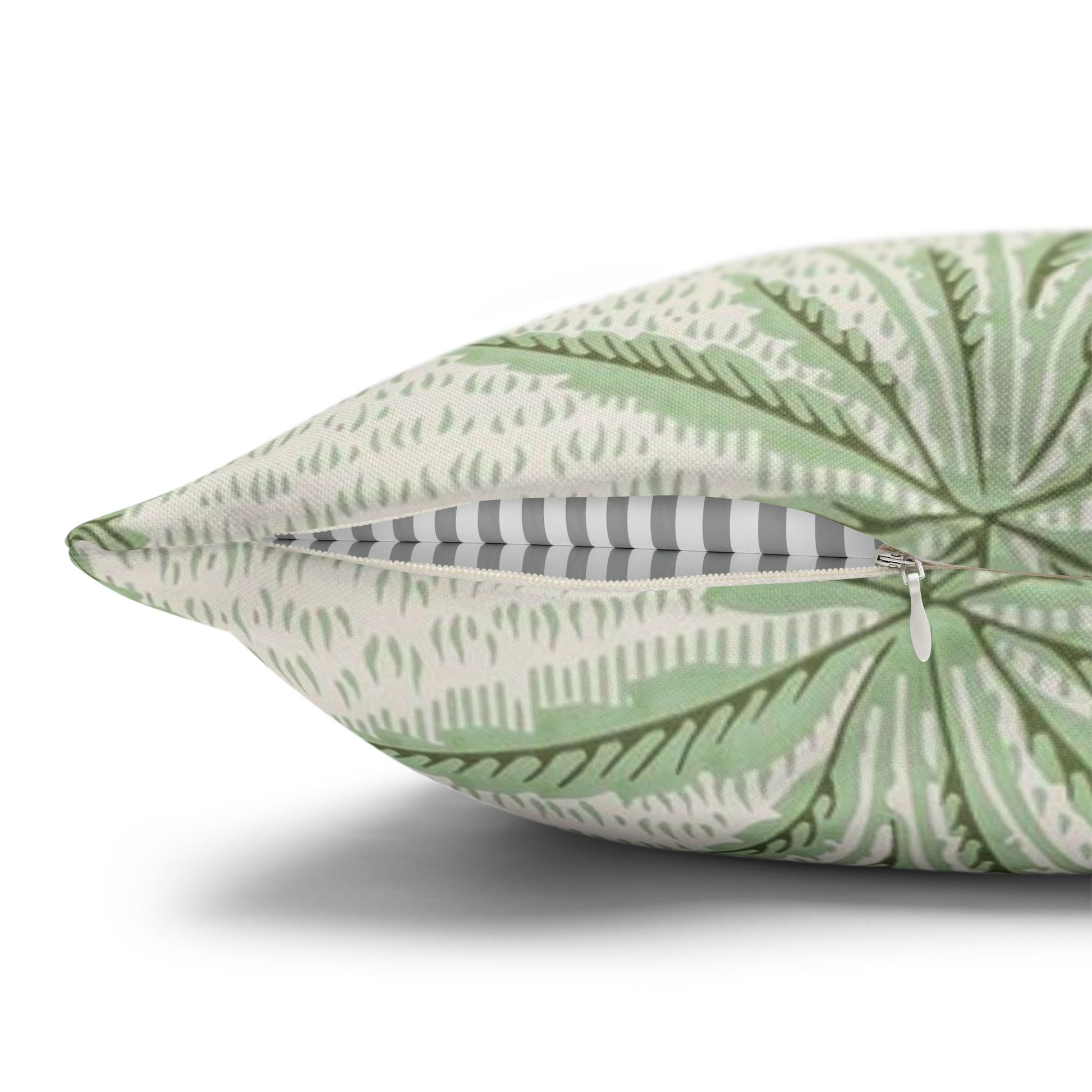 Green leaf-patterned pillow with a zipper on a white background