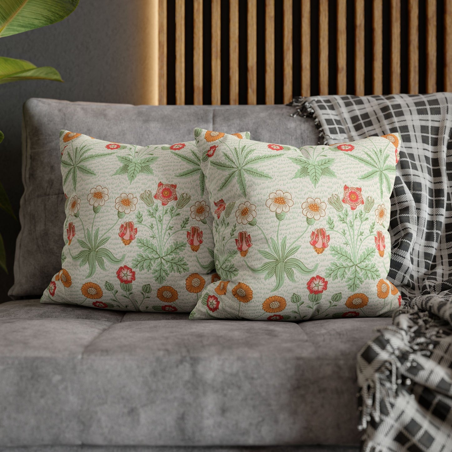 Floral-patterned pillows on a gray sofa with a wooden headboard in the background.