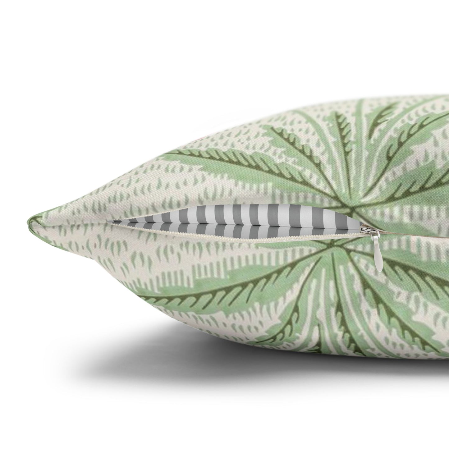 Green leaf-patterned pillow with a zipper on a white background