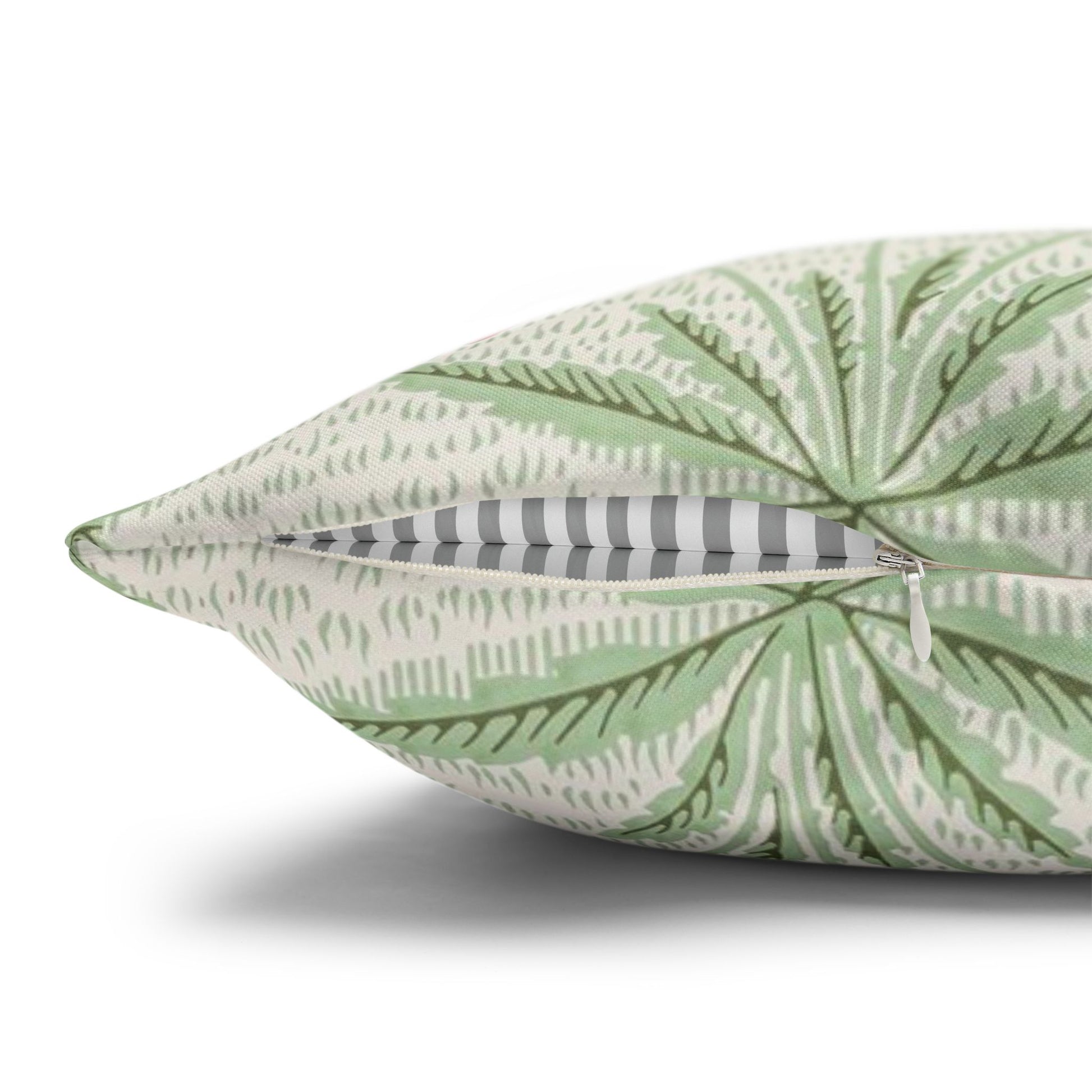 Green leaf-patterned pillow with a zipper on a white background