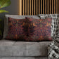 Decorative pillows with intricate patterns on a gray sofa against a wooden headboard.
